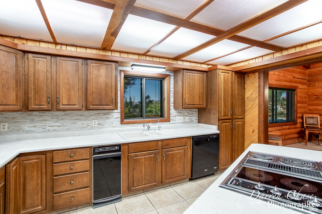 Kitchen featuring electric cooktop, sink, tasteful backsplash, and rustic walls