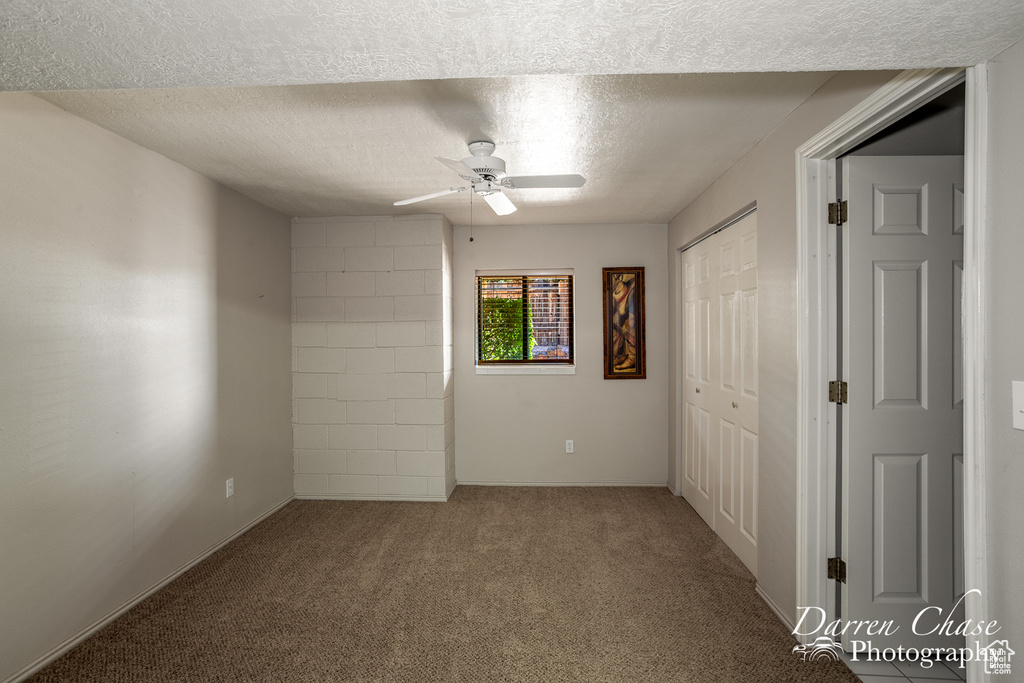 Carpeted spare room with a textured ceiling and ceiling fan