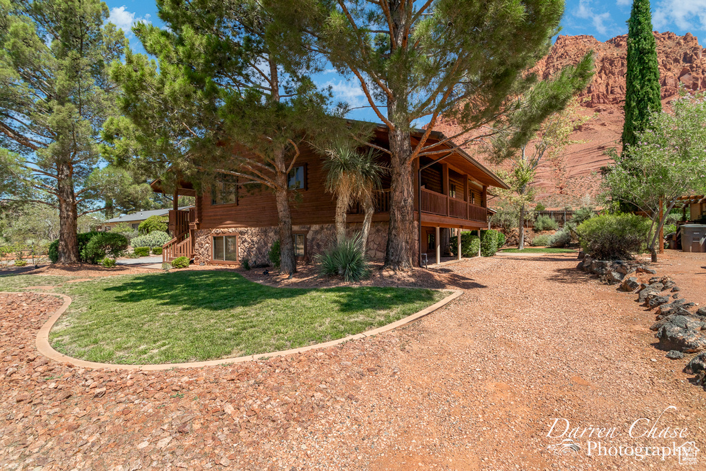 Back of property with a mountain view and a lawn