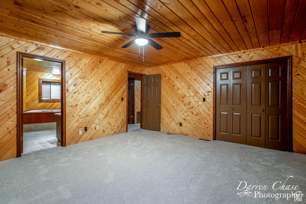 Bonus room featuring carpet flooring, wooden ceiling, ceiling fan, and wooden walls