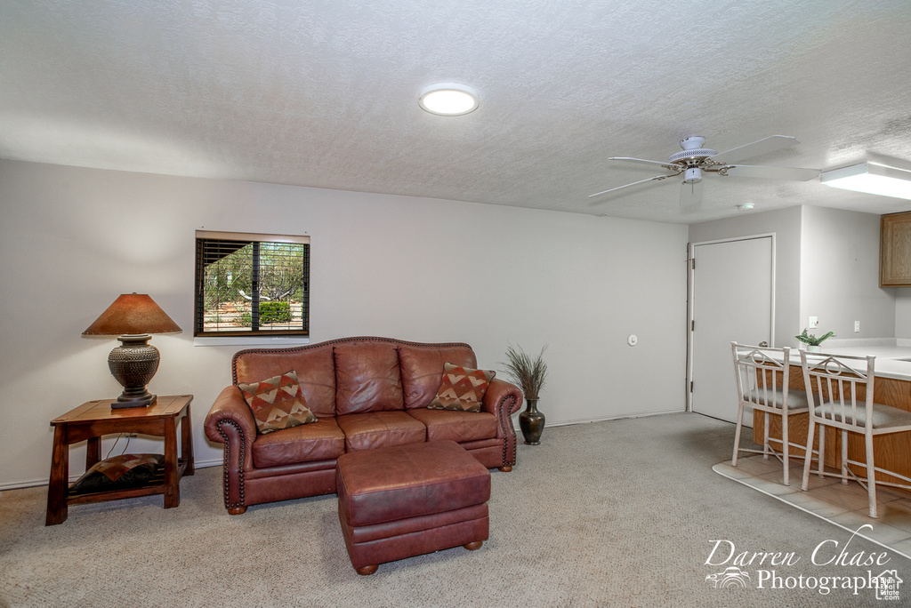 Carpeted living room with a textured ceiling and ceiling fan