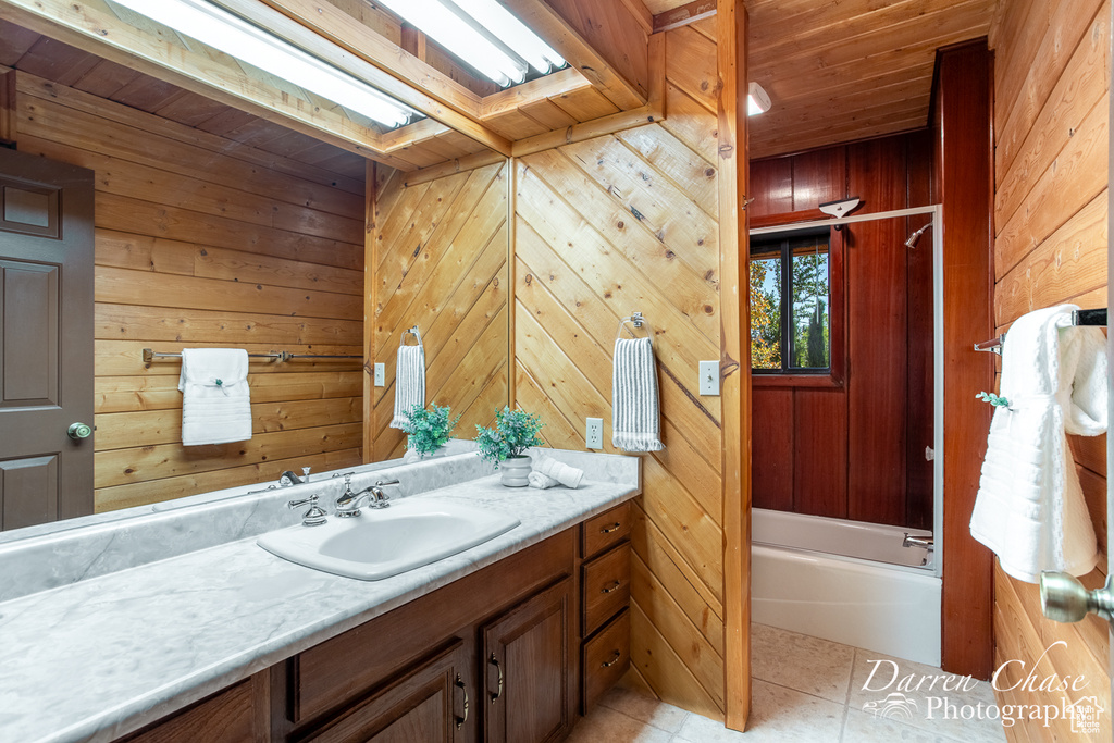 Bathroom featuring wooden walls, wood ceiling, tile patterned flooring, a skylight, and vanity