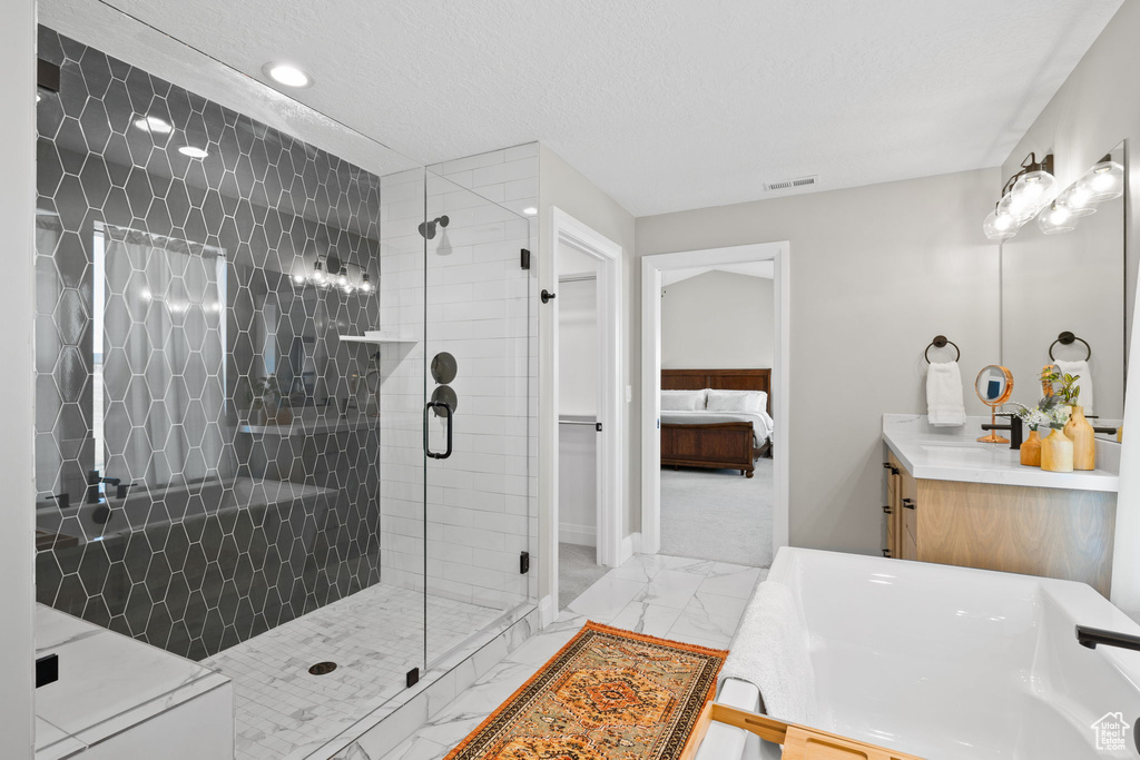 Bathroom featuring tile patterned floors, vanity, a shower with door, and a textured ceiling