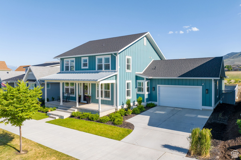 View of front of house featuring a porch, a garage, and a front lawn