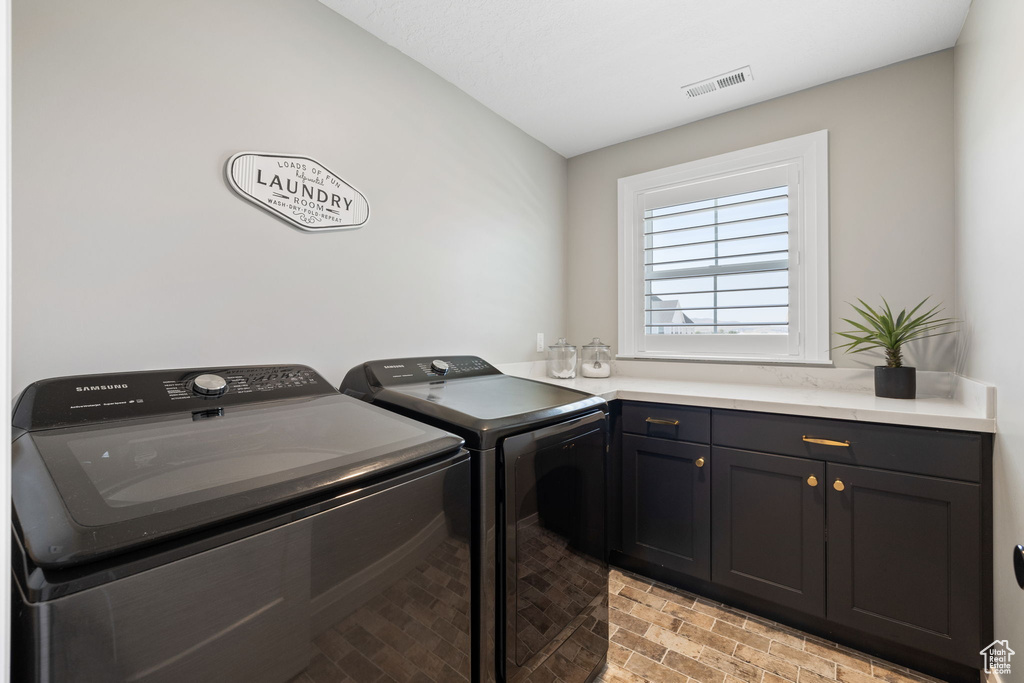 Washroom featuring washing machine and clothes dryer and cabinets