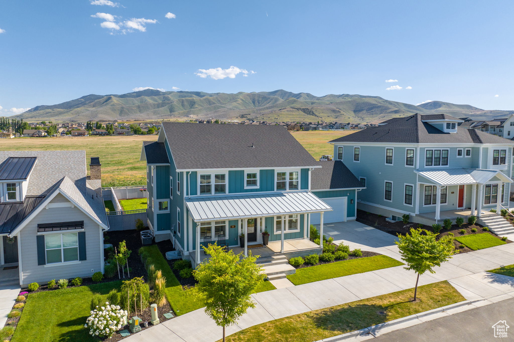 View of front of house with a garage, a mountain view, a front yard, and covered porch