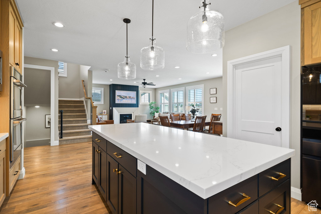 Kitchen featuring a center island, light hardwood / wood-style floors, decorative light fixtures, and light stone counters