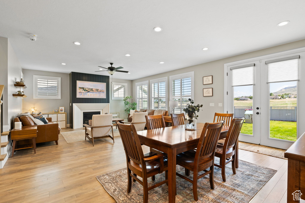 Dining space with ceiling fan, a fireplace, french doors, and light hardwood / wood-style flooring