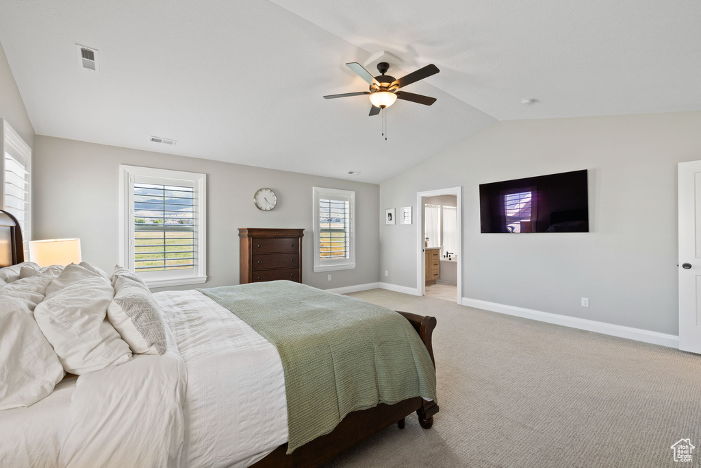 Carpeted bedroom with vaulted ceiling, ensuite bath, and ceiling fan