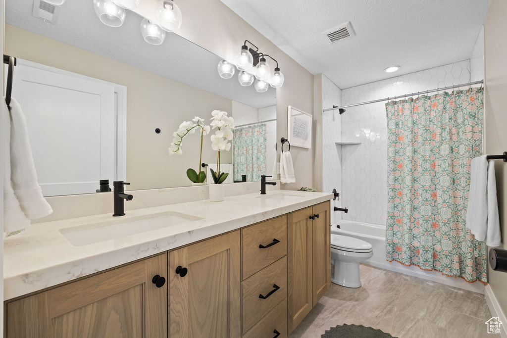 Full bathroom featuring shower / bath combination with curtain, tile patterned flooring, a textured ceiling, toilet, and double sink vanity