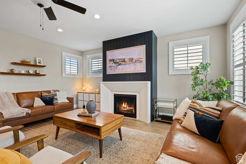 Living room with light wood-type flooring, ceiling fan, and a large fireplace