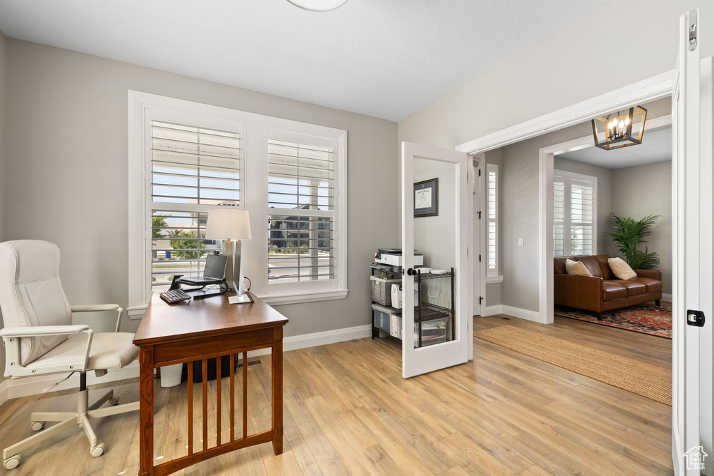 Office space with light hardwood / wood-style flooring and a chandelier