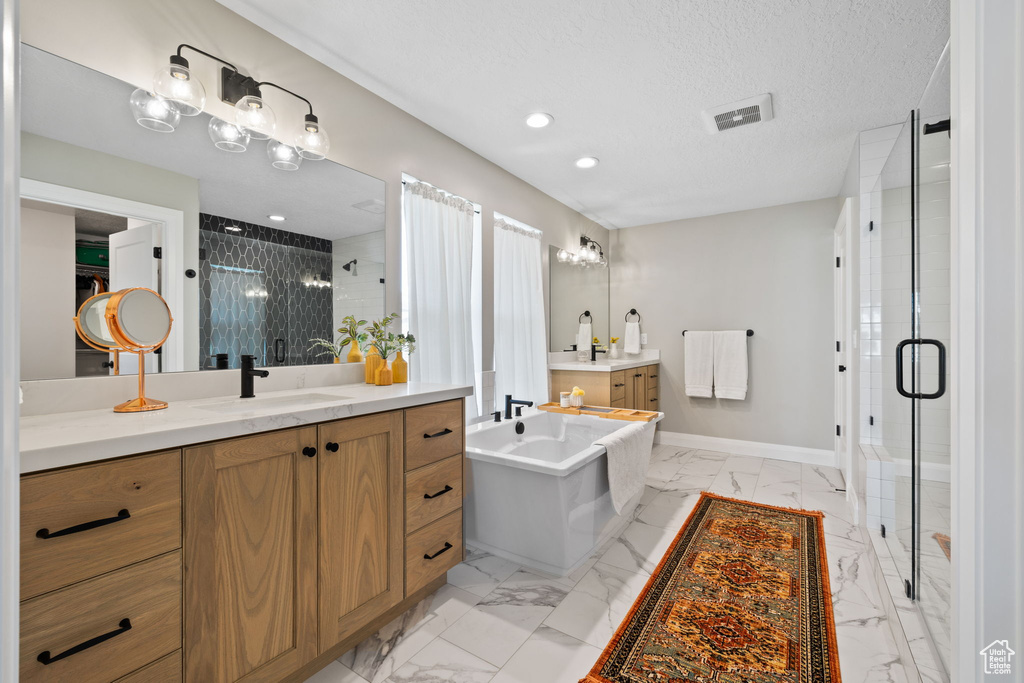 Bathroom with plus walk in shower, vanity, a textured ceiling, and tile patterned flooring