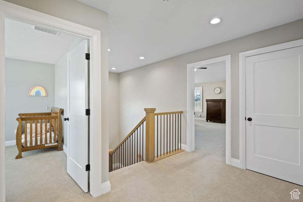 Corridor featuring light colored carpet