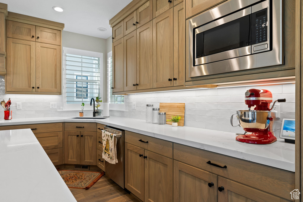 Kitchen featuring appliances with stainless steel finishes, dark hardwood / wood-style flooring, decorative backsplash, and sink