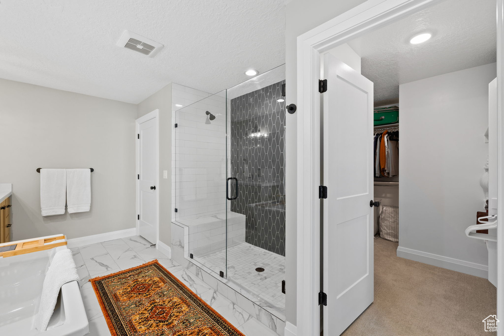 Bathroom featuring a shower with shower door, vanity, and a textured ceiling