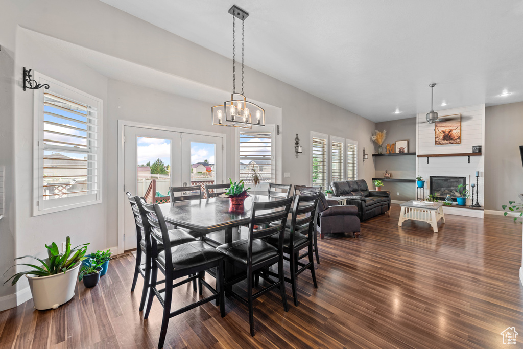 Dining space featuring a chandelier, hardwood / wood-style flooring, a large fireplace, and a healthy amount of sunlight