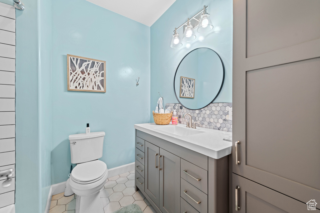 Bathroom featuring vanity, tile patterned floors, tasteful backsplash, and toilet