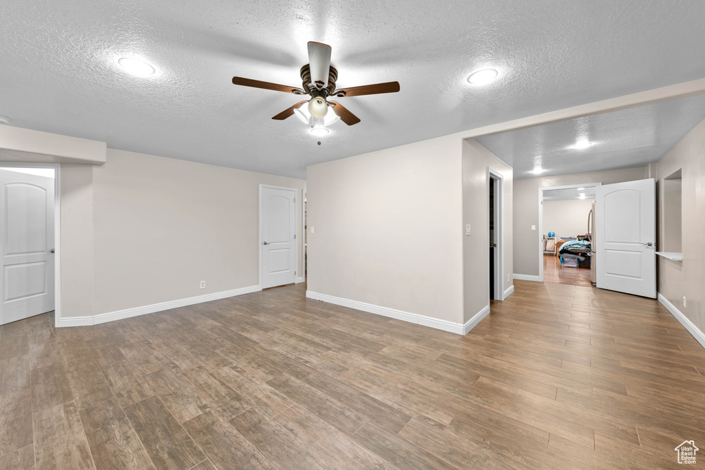 Basement featuring ceiling fan, a textured ceiling, and hardwood / wood-style flooring