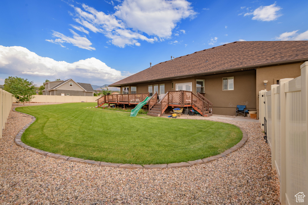 Rear view of house featuring a lawn and a wooden deck