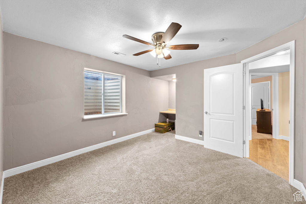 Unfurnished bedroom with ceiling fan and light colored carpet