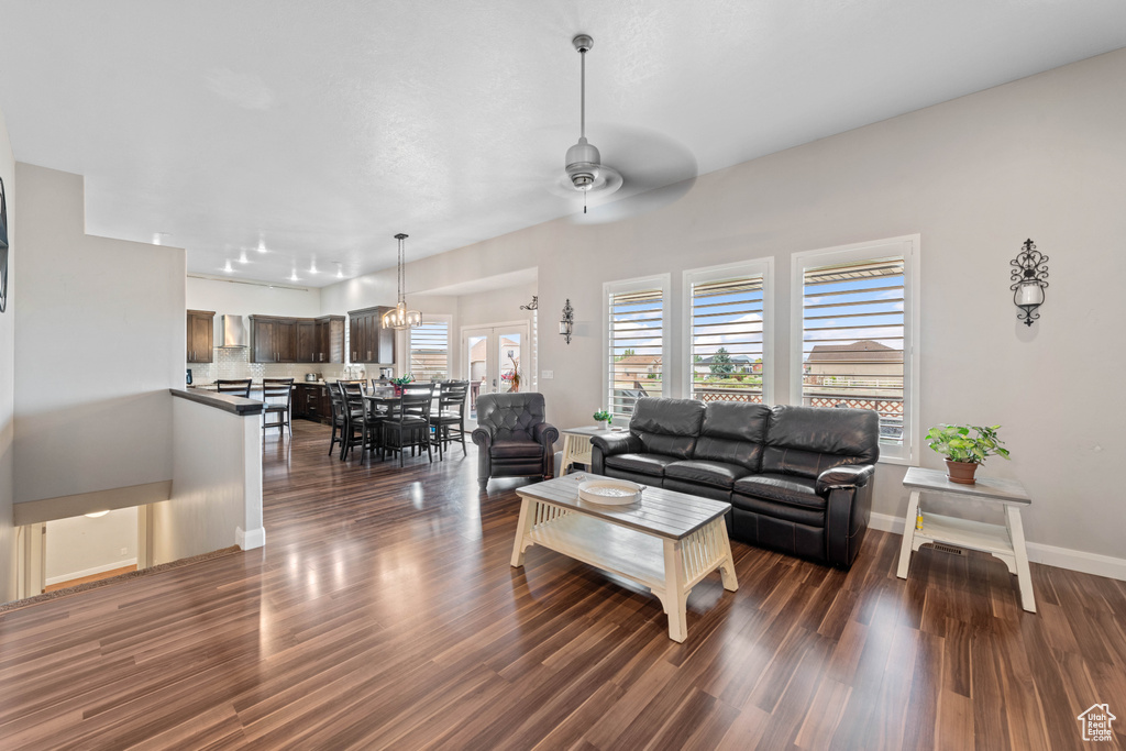 Living room with dark wood-type flooring and ceiling fan with notable chandelier