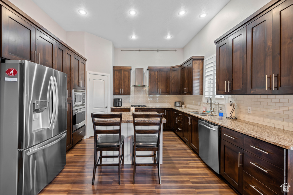 Kitchen with tasteful backsplash, wall chimney exhaust hood, sink, dark hardwood / wood-style floors, and appliances with stainless steel finishes