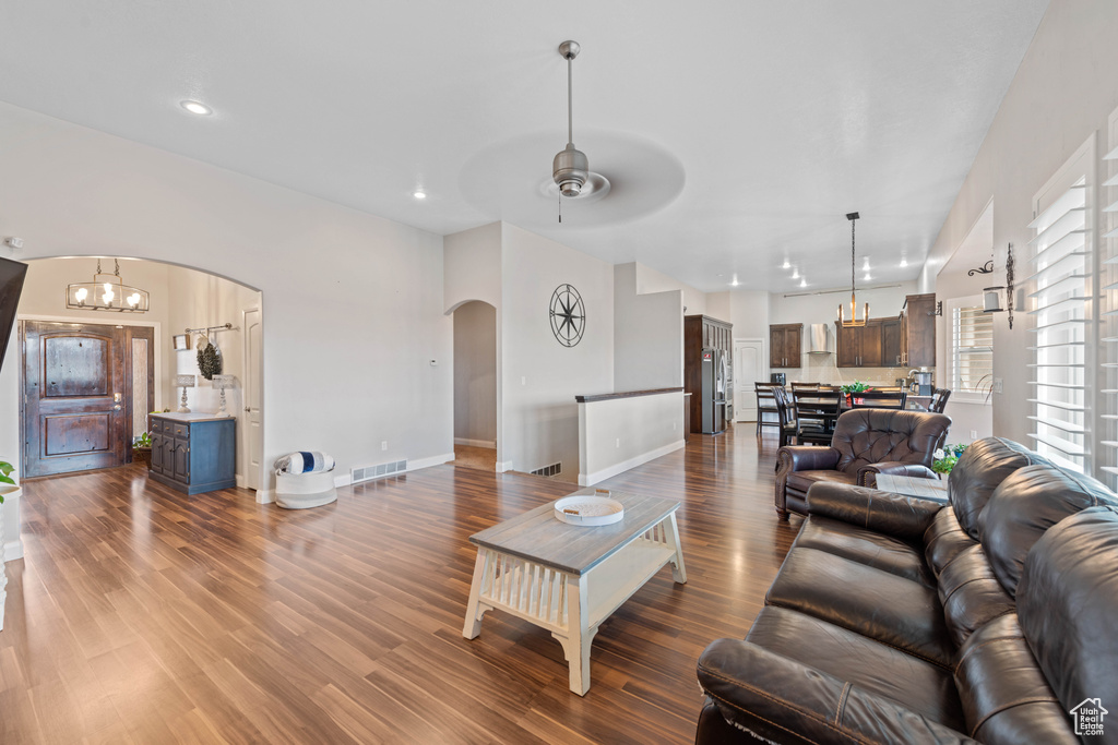 Living room with hardwood / wood-style flooring, a healthy amount of sunlight, and ceiling fan with notable chandelier