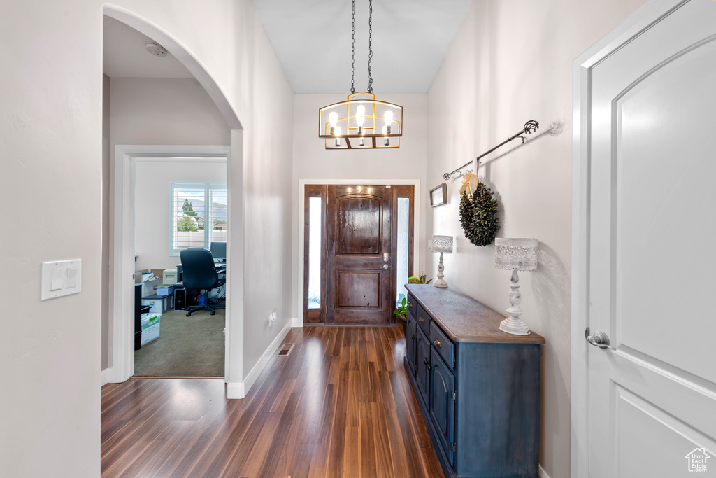 Entrance foyer featuring dark colored carpet and a notable chandelier