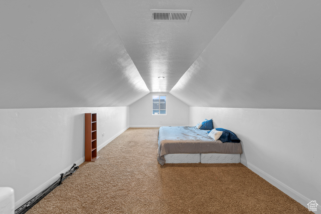 Bedroom with carpet flooring and lofted ceiling