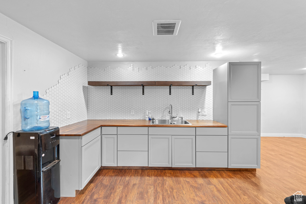 Kitchen featuring sink, light hardwood / wood-style flooring, wood counters, and backsplash