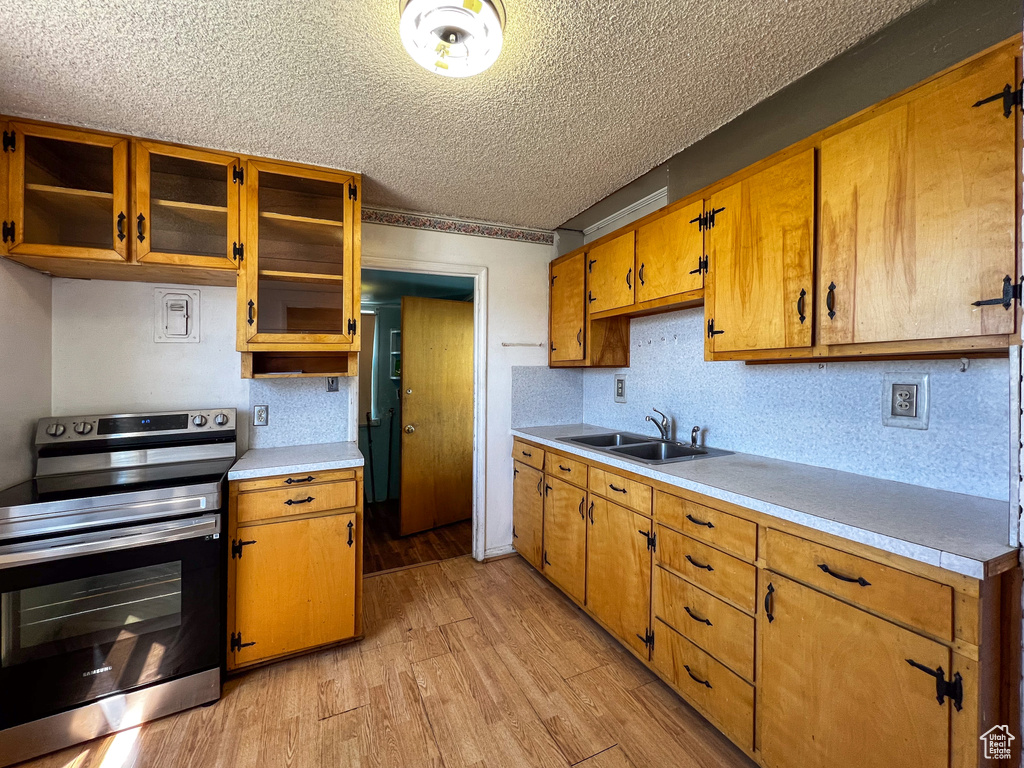 Kitchen featuring sink, a textured ceiling, light hardwood / wood-style flooring, and stainless steel electric stove