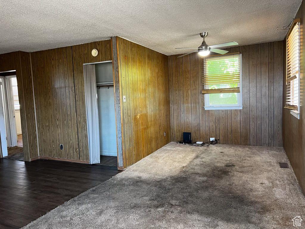 Empty room with wood walls, dark hardwood / wood-style flooring, and a wealth of natural light