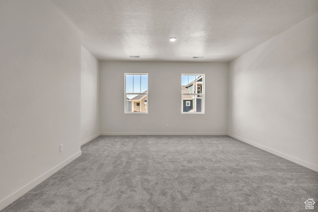 Unfurnished room with a textured ceiling and light carpet