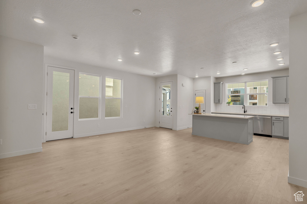 Unfurnished living room with a textured ceiling, light hardwood / wood-style floors, and sink