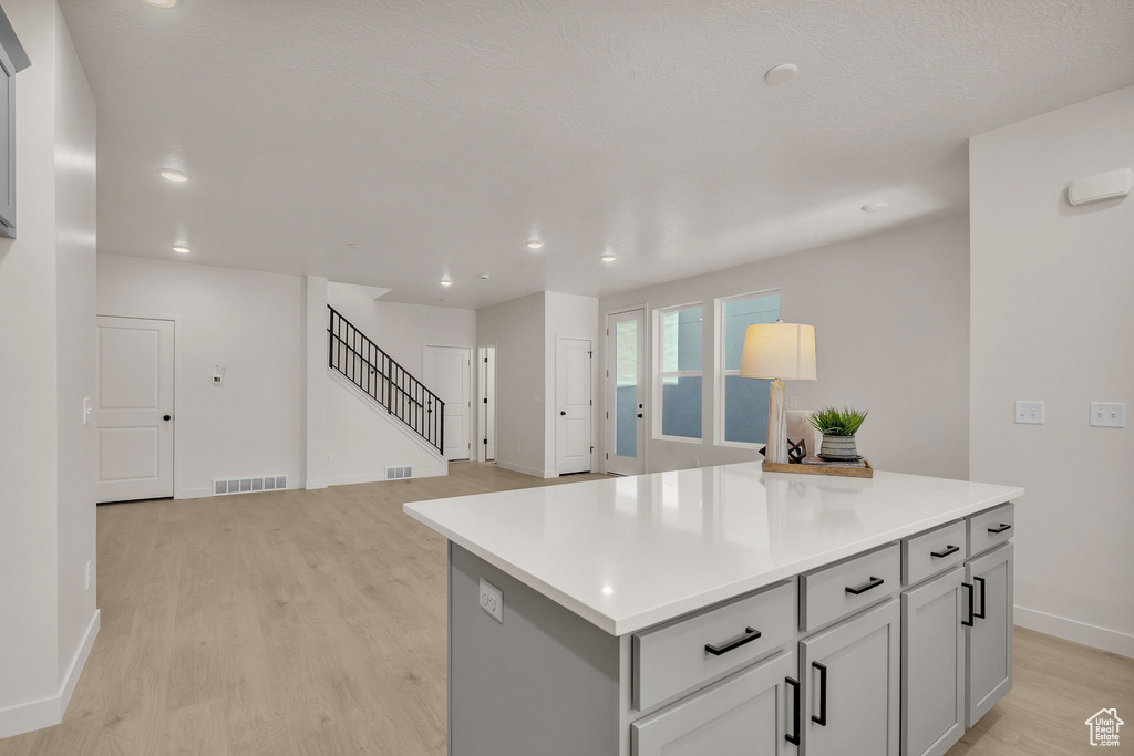 Kitchen with gray cabinets, light hardwood / wood-style floors, and a kitchen island