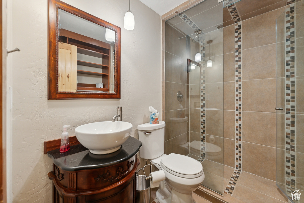 Bathroom with a shower with shower door, toilet, and vanity