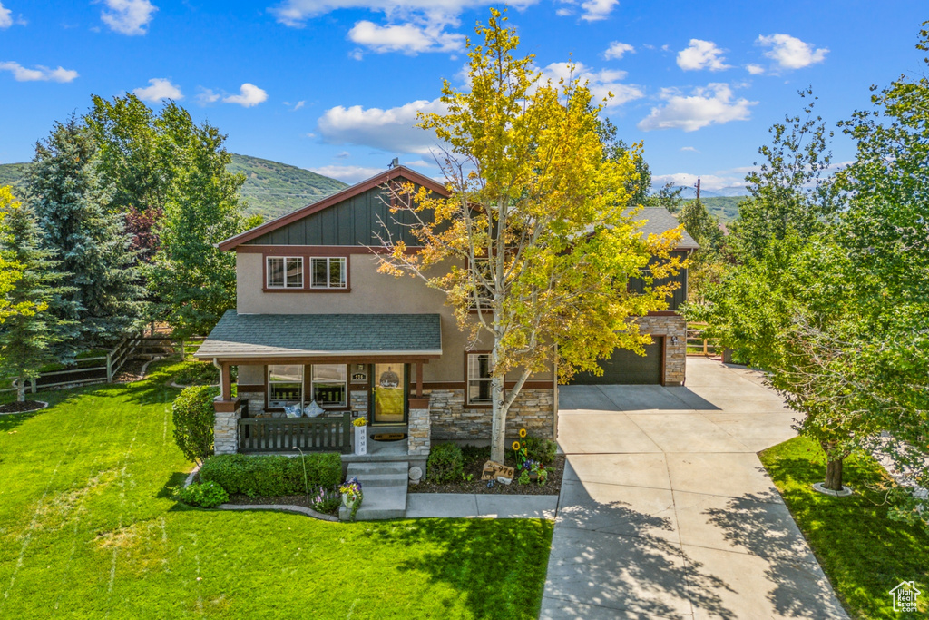 View of front facade featuring a mountain view, a porch, a garage, and a front yard