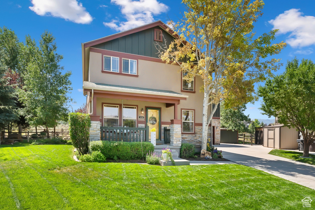 View of front of property featuring a front yard and a storage shed