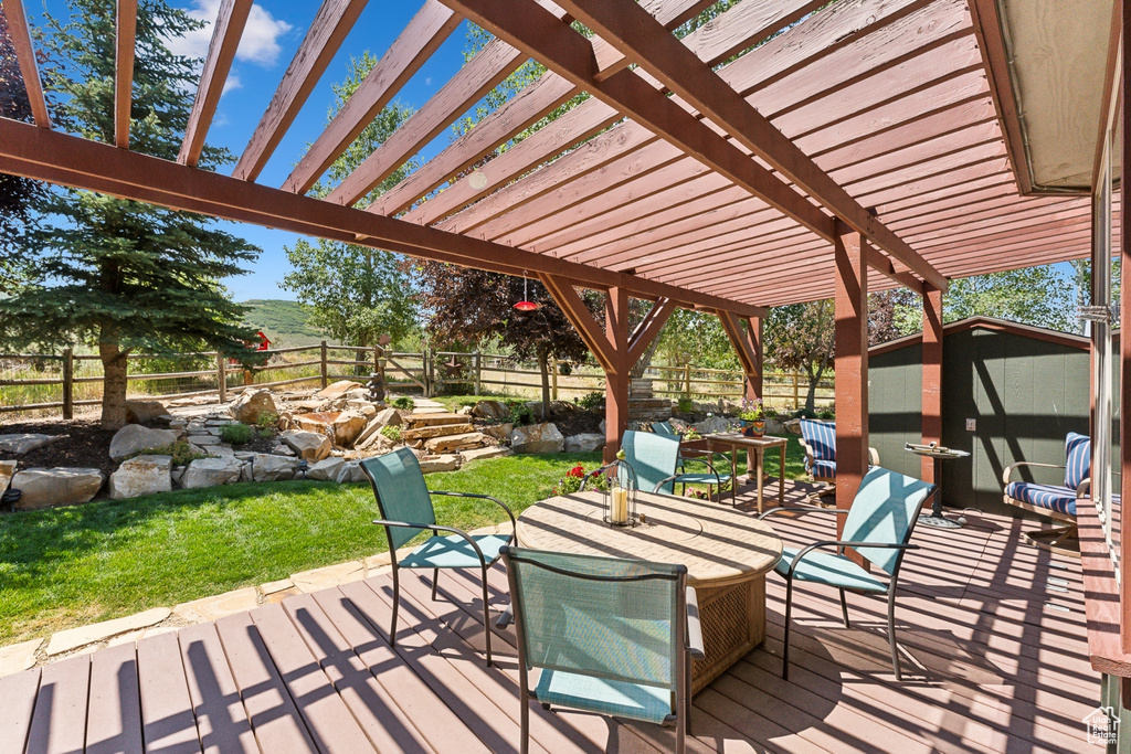 Wooden deck featuring a pergola and a storage shed