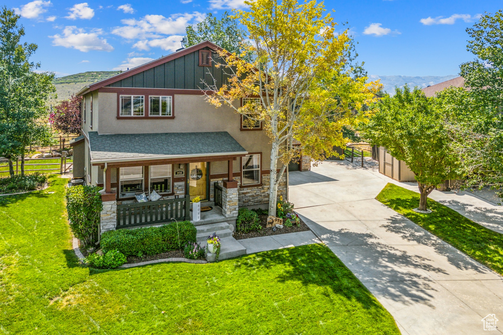 View of front of property featuring a mountain view, covered porch, and a front lawn