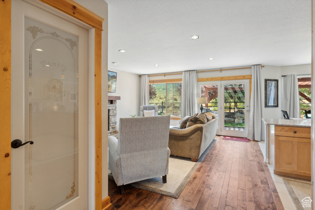 Living room with a stone fireplace, wood-type flooring, and a wealth of natural light