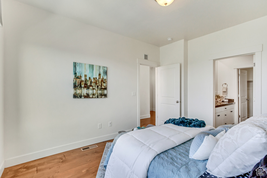 Bedroom with ensuite bathroom and hardwood / wood-style floors