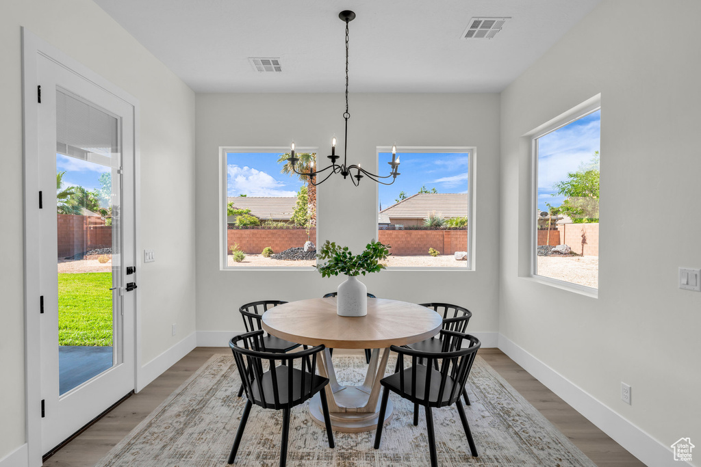 Dining room with hardwood / wood-style floors, a chandelier, and a healthy amount of sunlight