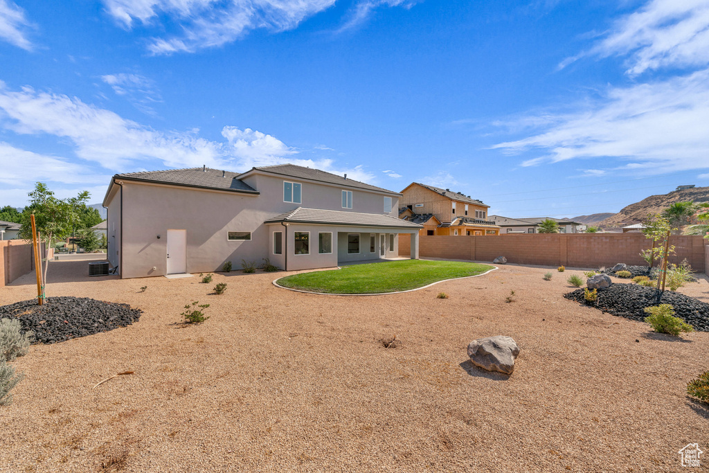 Rear view of property with central AC and a lawn