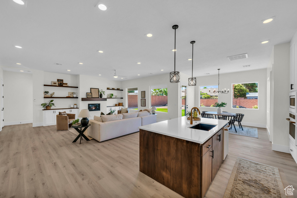 Kitchen with sink, light wood-type flooring, a center island with sink, and plenty of natural light