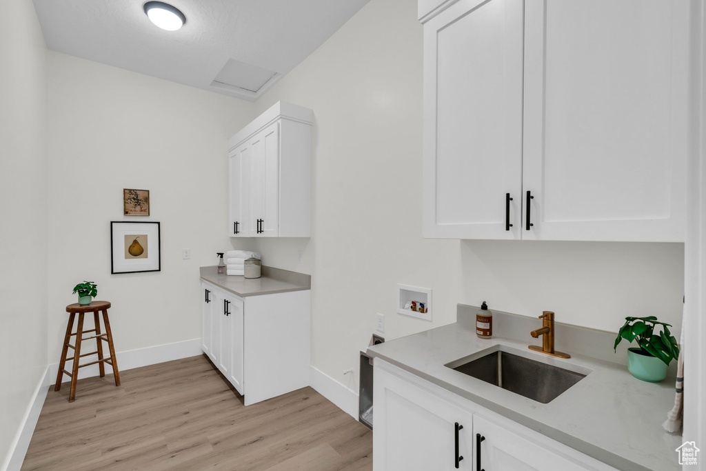 Kitchen featuring sink, light hardwood / wood-style flooring, white cabinets, and light stone countertops