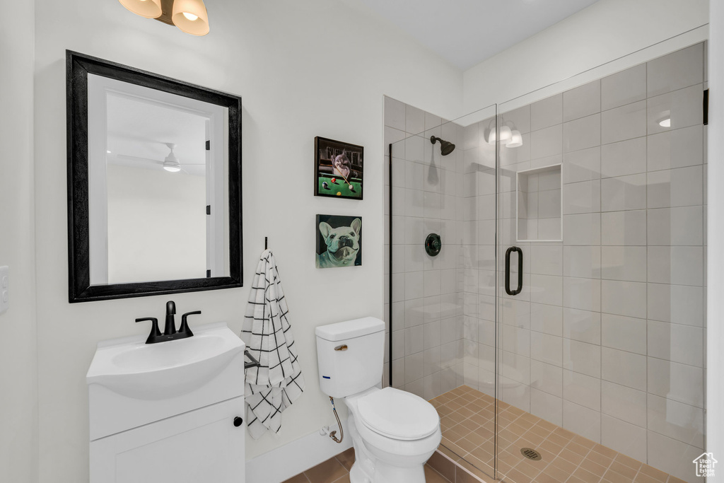 Bathroom featuring a shower with door, toilet, and vanity