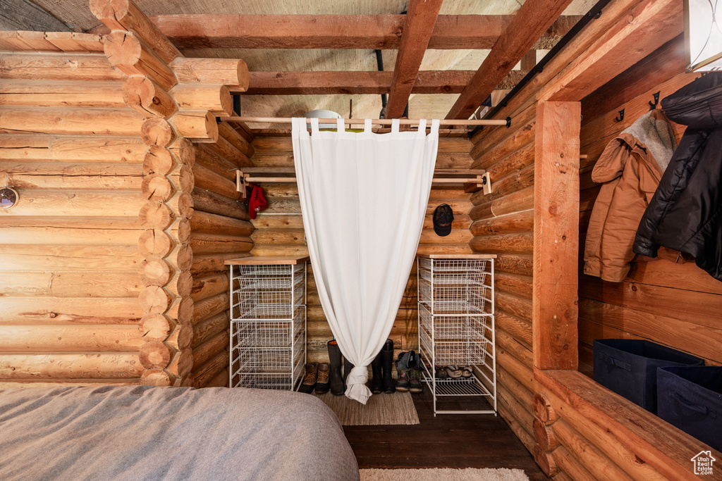 Unfurnished bedroom featuring beam ceiling, wooden ceiling, wood-type flooring, and rustic walls