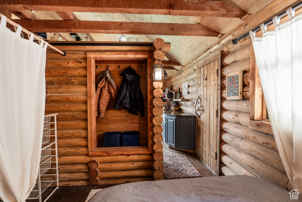 Interior space featuring lofted ceiling with beams, hardwood / wood-style floors, and log walls